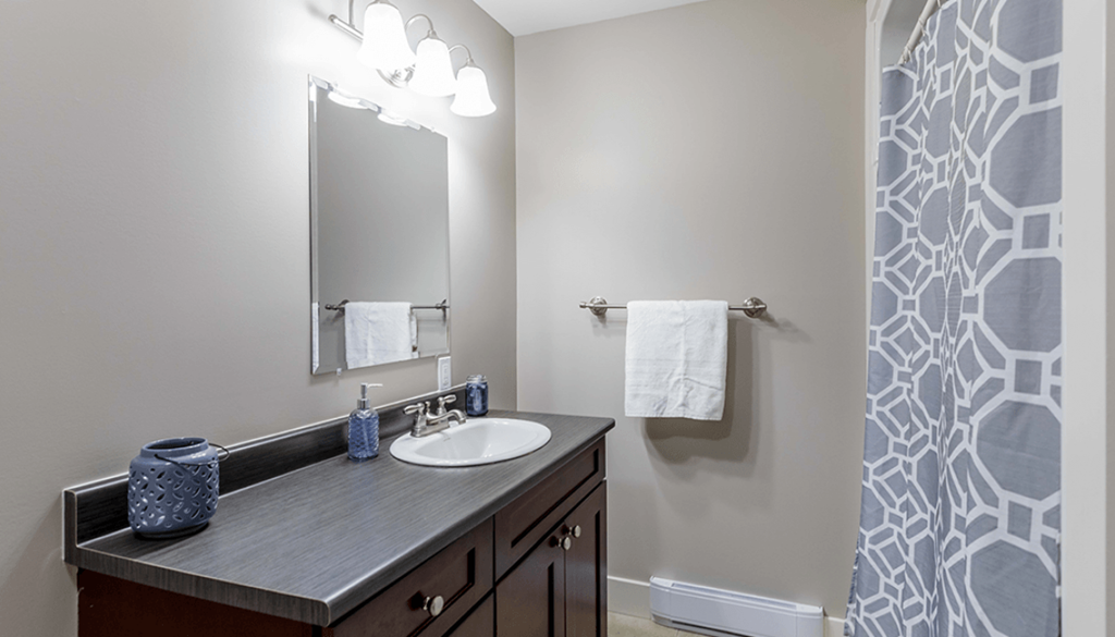 A bathroom with a sink, mirror, and a blue vase.