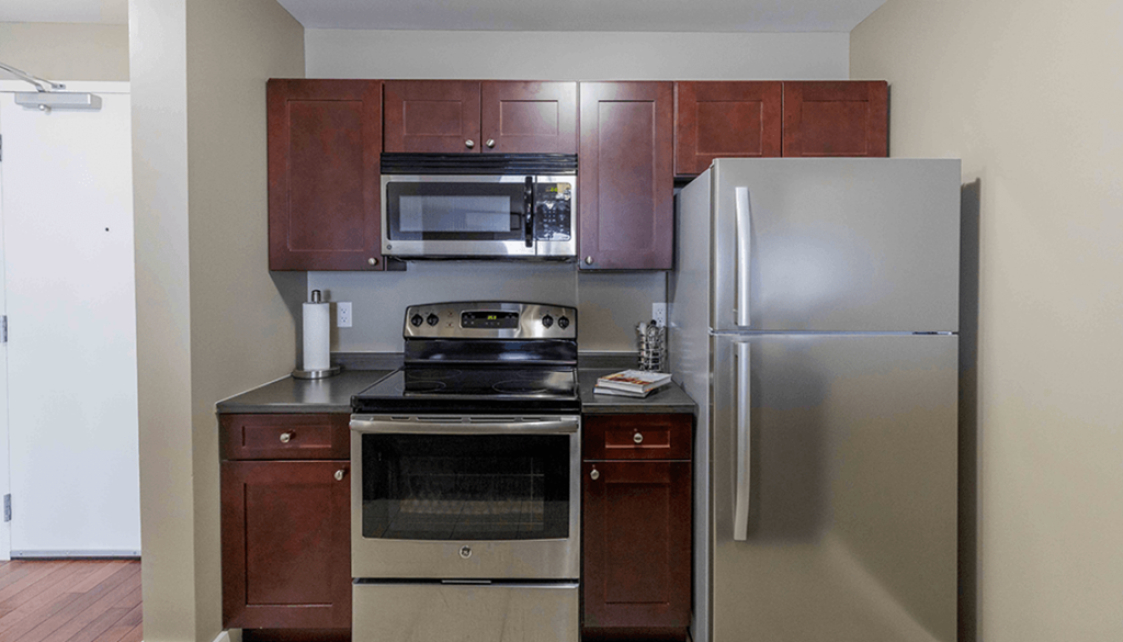 A kitchen with a refrigerator, oven, and microwave.