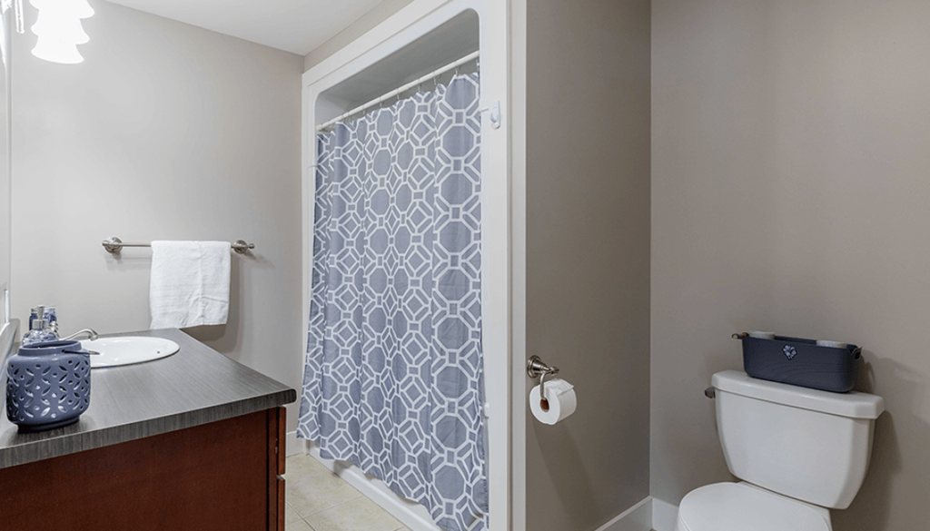 A bathroom with a toilet, sink, and shower curtain.