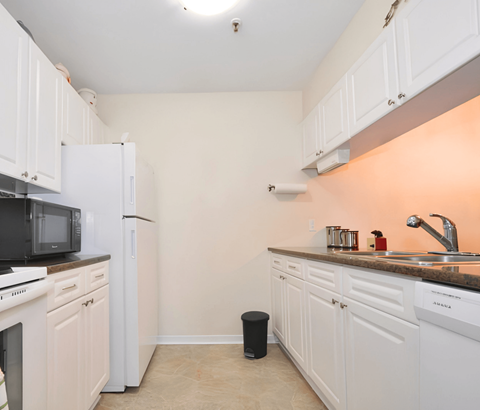 A kitchen with white cabinets and appliances.