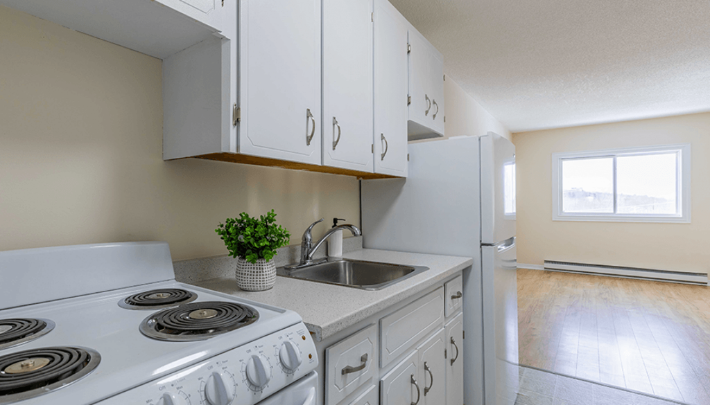A white stove and sink in a kitchen with wooden floors.