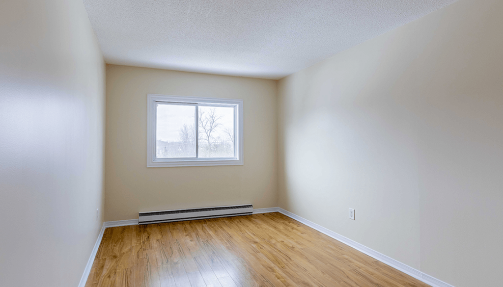 Empty room with a window and wooden floor.