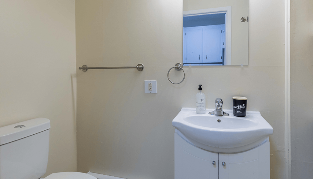 A white sink with a mirror above it and a toilet to the left.