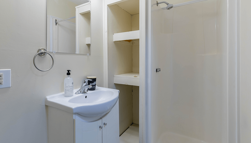 A white bathroom with a sink and mirror.