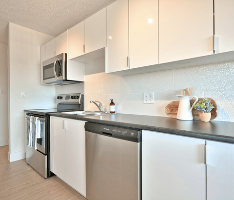 A modern kitchen with white cabinets and stainless steel appliances.