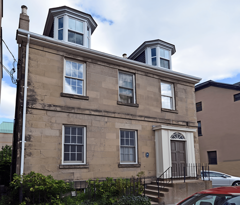 A beige building with a brown door and windows.