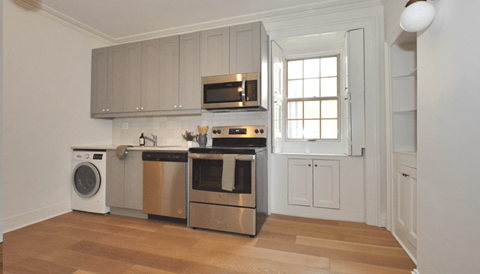 A modern kitchen with stainless steel appliances and wooden flooring.
