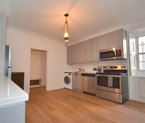A kitchen with a white counter top and stainless steel appliances.