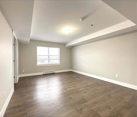 A room with a window and wooden flooring.