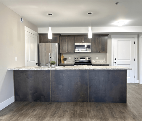 A modern kitchen with a dark island and stainless steel appliances.