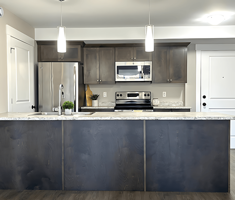 A modern kitchen with a dark grey countertop and stainless steel appliances.
