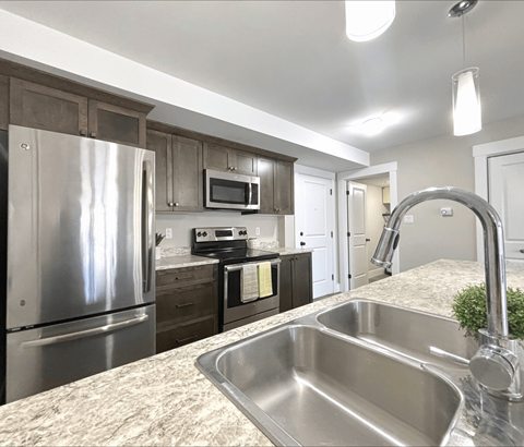 A kitchen with a stainless steel sink and refrigerator.