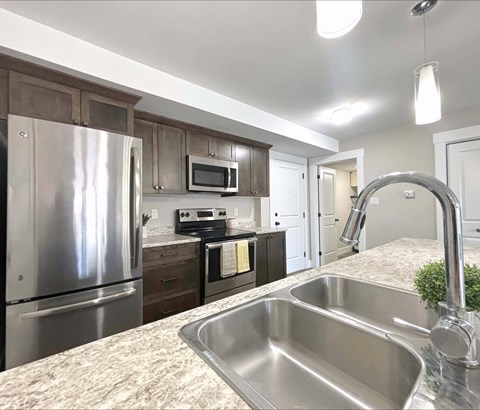 A kitchen with a stainless steel sink and refrigerator.