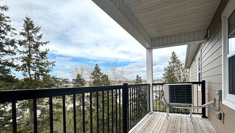 A balcony with a black railing and a black chair with a white armrest.