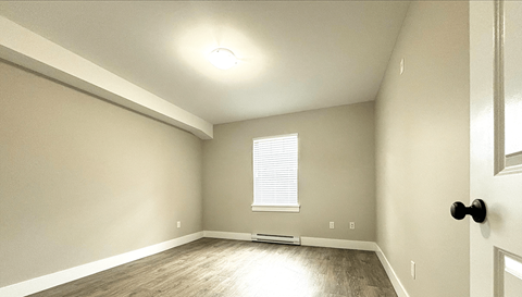 A room with a door, window, and light switches.