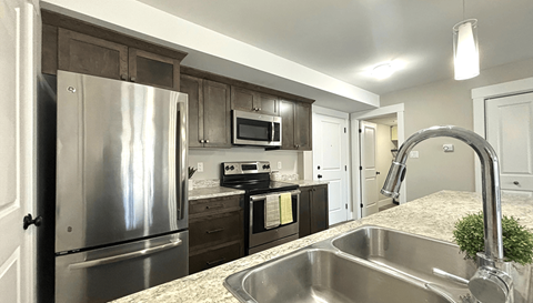 A kitchen with a stainless steel refrigerator and sink.