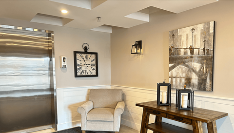 A living room with a chair, table, and pictures on the wall.