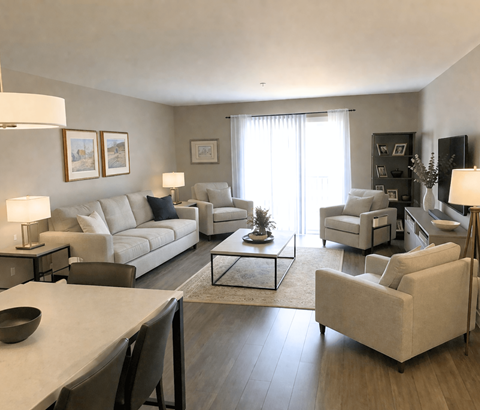 A living room with a white couch, a coffee table, and a television.