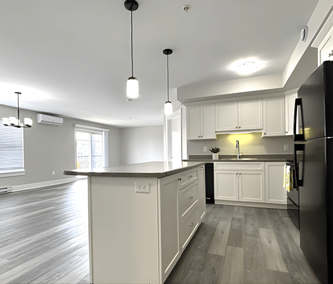 A kitchen with a black refrigerator and white cabinets.