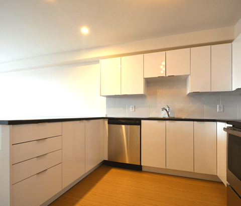 A kitchen with white cabinets and a black countertop.