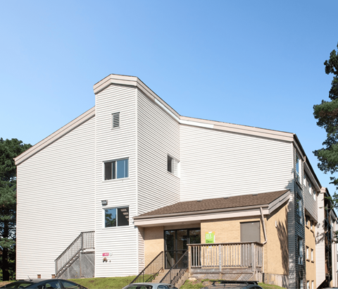 A white building with a brown roof and a sign on the front.