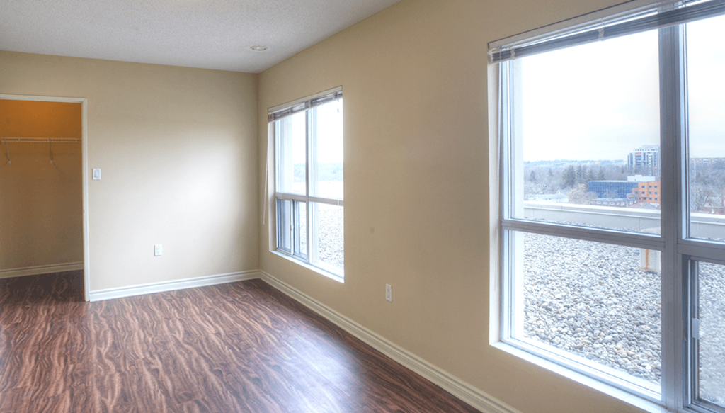 an empty living room with large windows and a wood floor