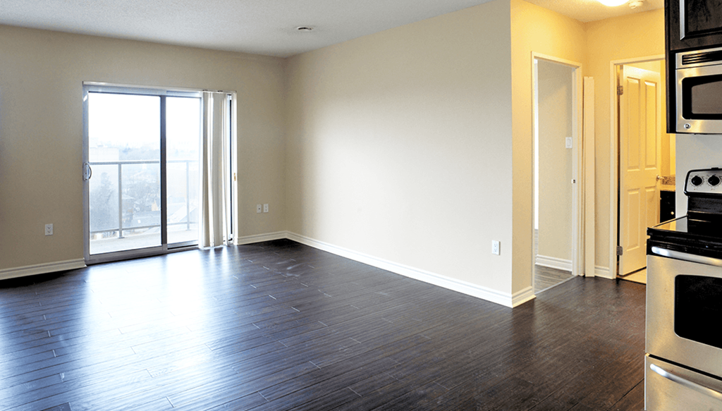 an empty living room with wood flooring and a door to a balcony