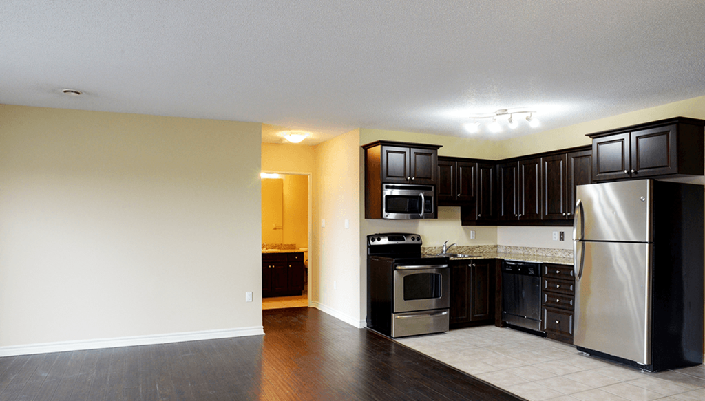 an empty kitchen with black cabinets and stainless steel appliances