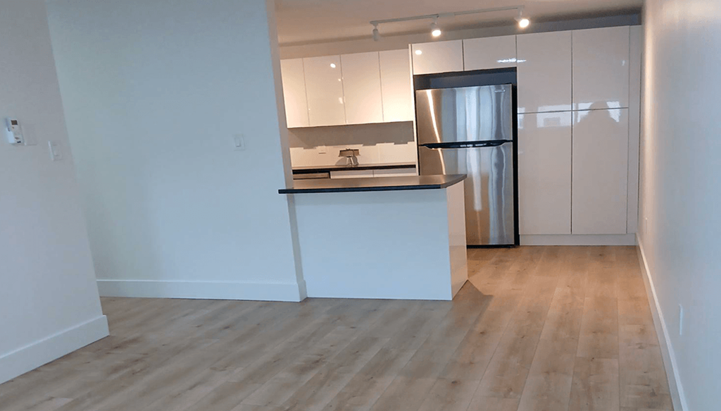 A kitchen with a refrigerator, sink, and cabinets.