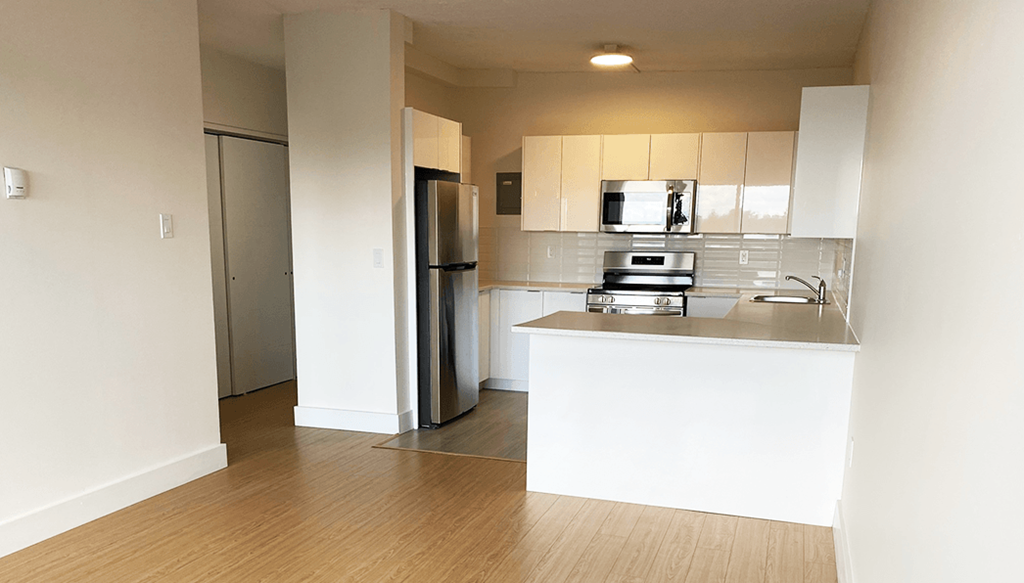 A kitchen with white cabinets and a wooden floor.