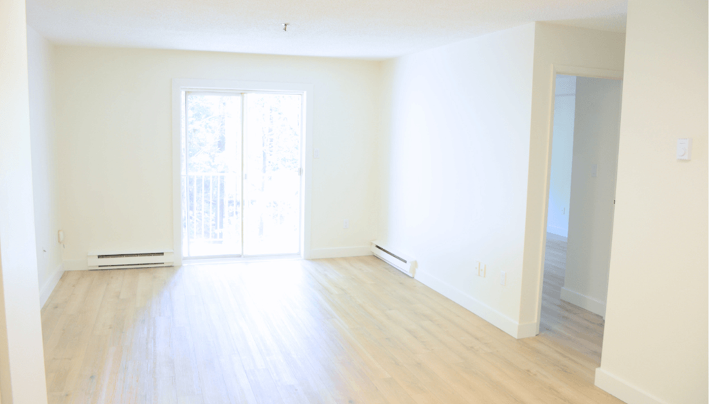 A room with a sliding glass door and wooden flooring.