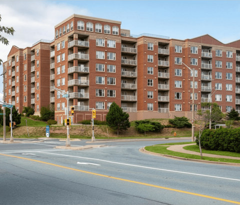 A large red brick apartment building with a street in front of it.