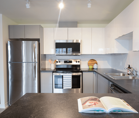 A modern kitchen with a refrigerator, oven, and microwave.
