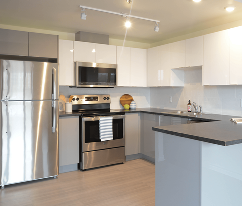 A modern kitchen with a stainless steel refrigerator and a microwave above the stove.