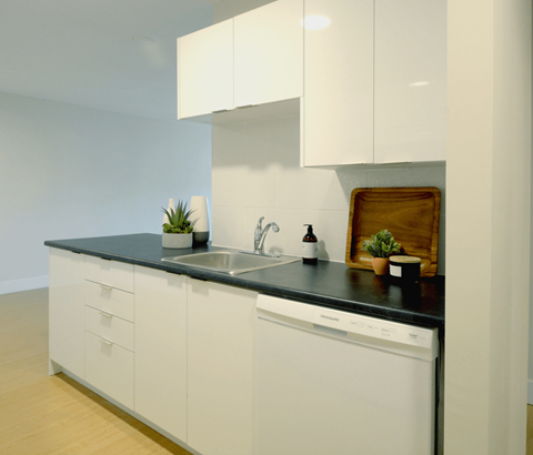 A modern kitchen with white cabinets and a black countertop.