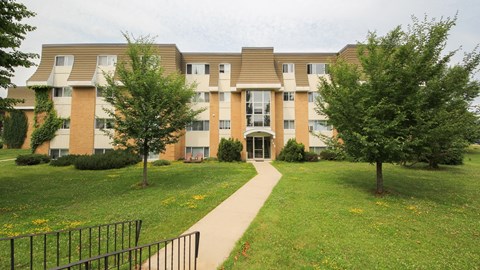 an apartment building with a sidewalk and trees in front of it