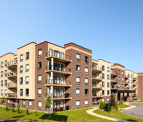 Apartment buildings with balconies and green lawns in front.
