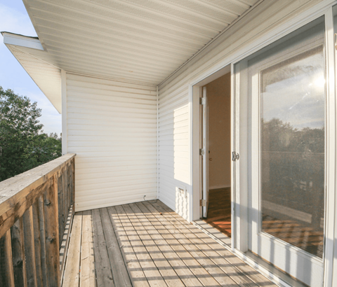 A white screened porch with a wooden railing.
