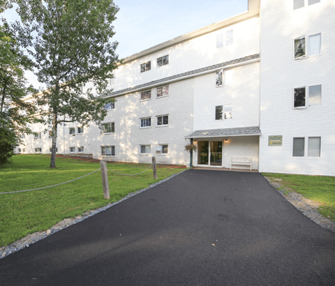 A white building with a black driveway in front.