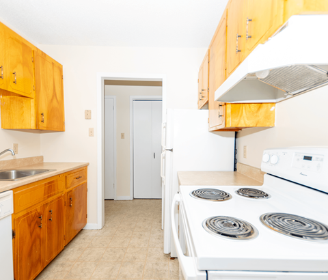 A kitchen with a white stove and wooden cabinets.
