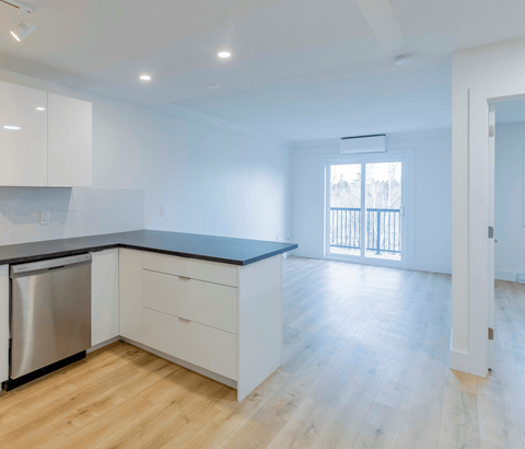 A kitchen with white cabinets and a black countertop.