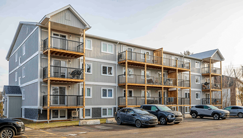 Apartment building with cars parked in front.