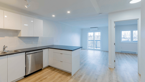 A kitchen with white cabinets and a black countertop.