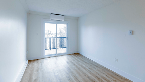 A room with a sliding glass door leading to a balcony.