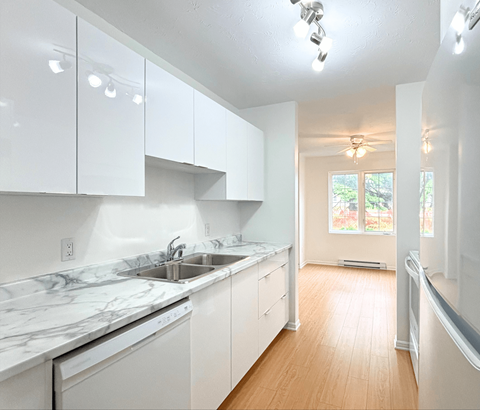 A kitchen with white cabinets and marble countertops.