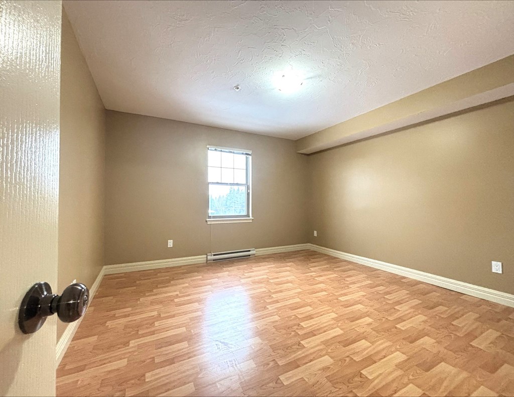 A room with wooden flooring and a window.