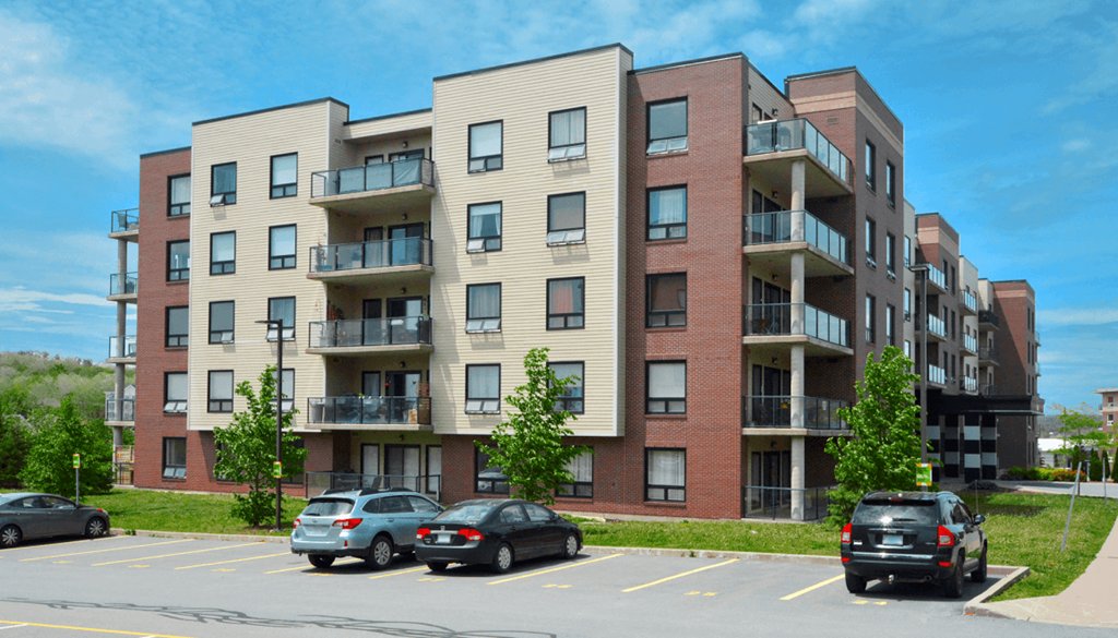 an apartment building with cars parked in a parking lot