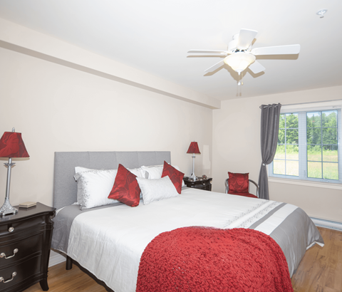 A bedroom with a large bed and a ceiling fan.