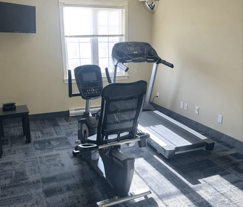 A treadmill and a stationary bike are in a room with a window.