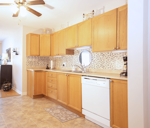 A kitchen with wooden cabinets and a white dishwasher.